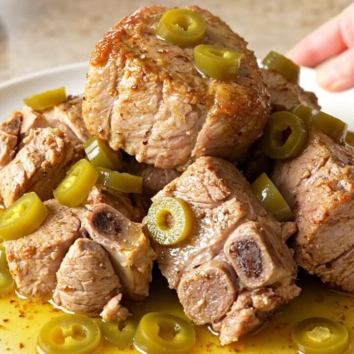 A close-up shot of a tender, slow-cooked Mississippi pork roast with pepperoncini in a slow cooker.