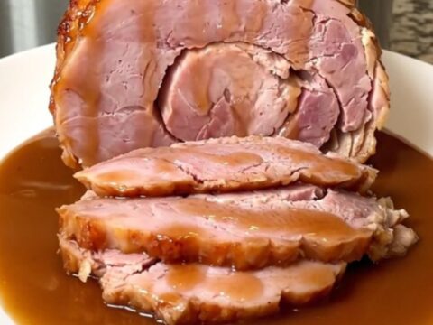 A close-up of a spiral-sliced ham in a slow cooker covered in a shiny brown sugar and cinnamon glaze.