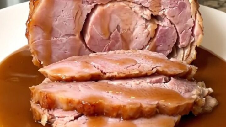 A close-up of a spiral-sliced ham in a slow cooker covered in a shiny brown sugar and cinnamon glaze.