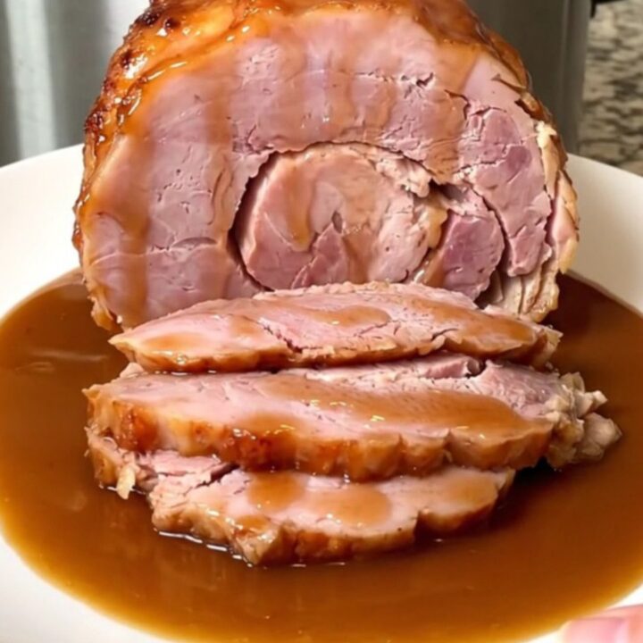 A close-up of a spiral-sliced ham in a slow cooker covered in a shiny brown sugar and cinnamon glaze.