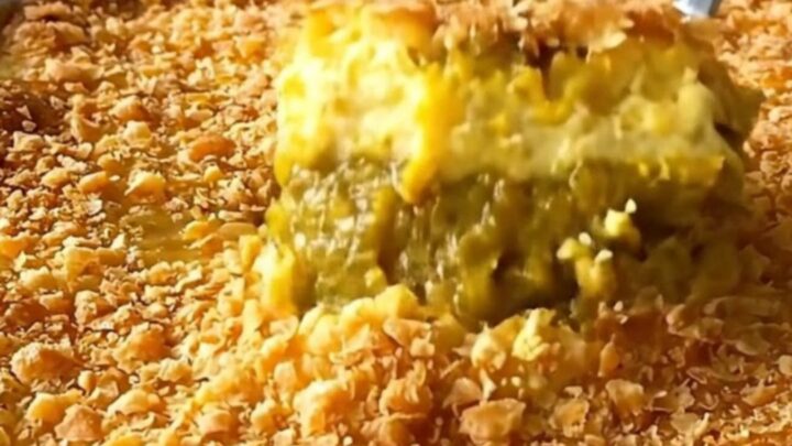 A close-up of a freshly baked pumpkin dump cake with a golden, crispy brown butter topping in a white baking dish.