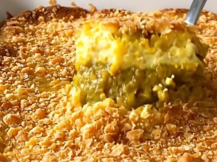 A close-up of a freshly baked pumpkin dump cake with a golden, crispy brown butter topping in a white baking dish.