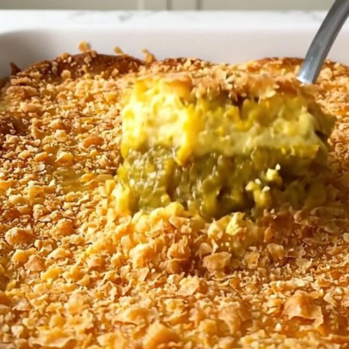 A close-up of a freshly baked pumpkin dump cake with a golden, crispy brown butter topping in a white baking dish.