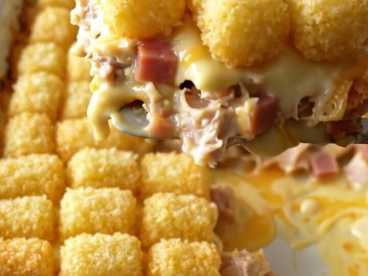 A top-down view of a creamy Chicken Cordon Bleu Potato Tot Bake in a rectangular ceramic dish.