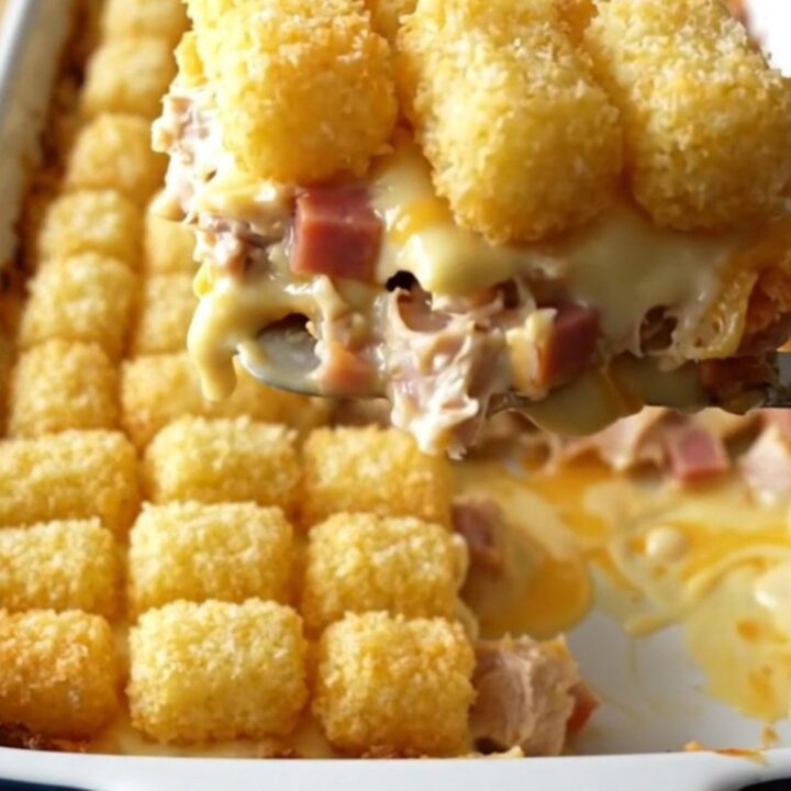 A top-down view of a creamy Chicken Cordon Bleu Potato Tot Bake in a rectangular ceramic dish.