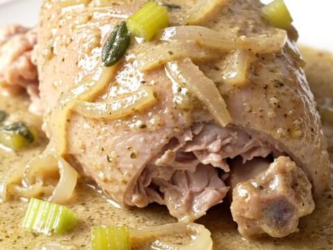 A close-up of tender, braised turkey tenderloins in a creamy, herb-flecked sauce.