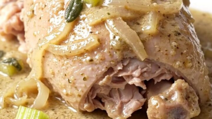 A close-up of tender, braised turkey tenderloins in a creamy, herb-flecked sauce.
