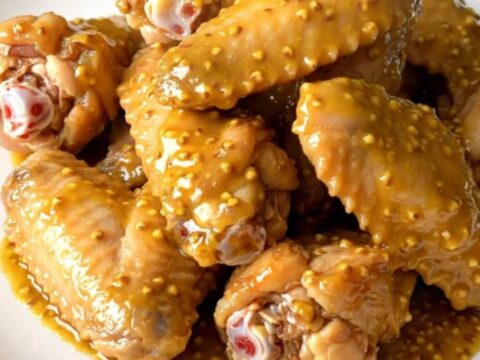 A platter of tender, golden-brown chicken wings coated in a rich mustard barbecue sauce, freshly served.