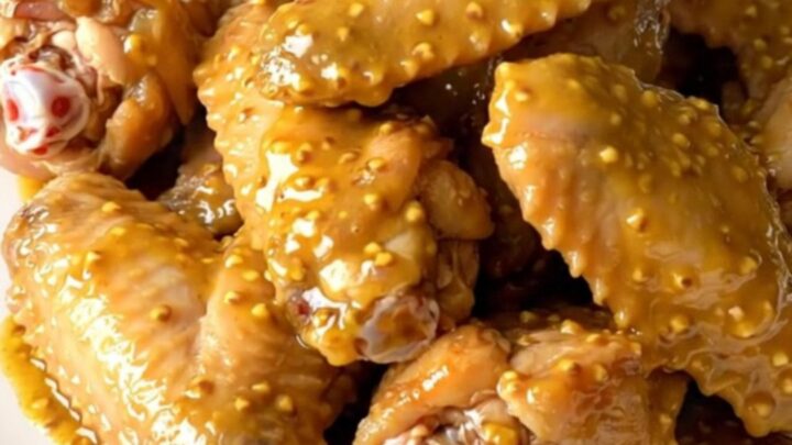 A platter of tender, golden-brown chicken wings coated in a rich mustard barbecue sauce, freshly served.