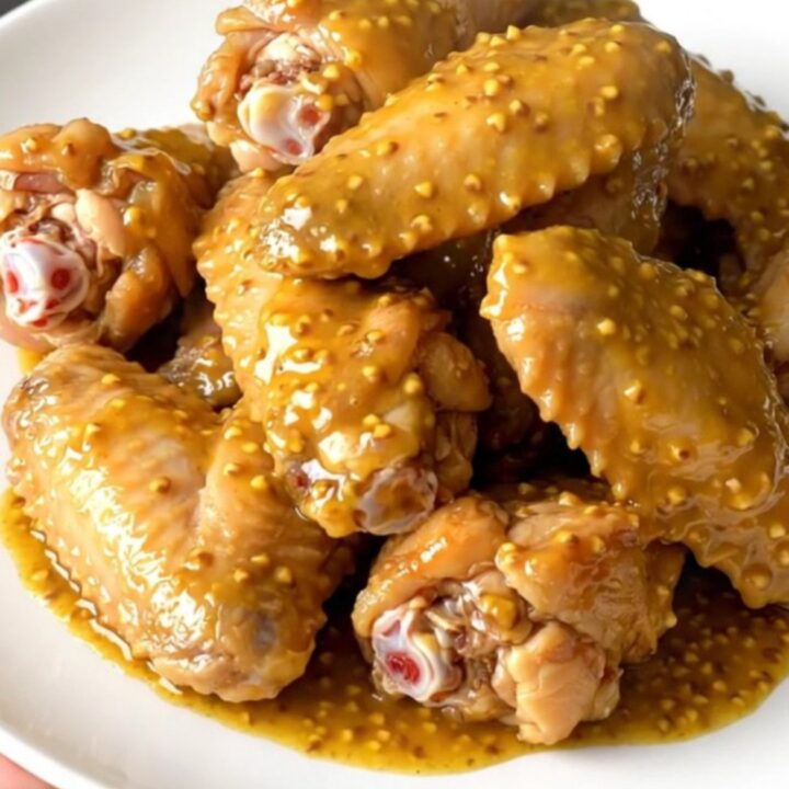 A platter of tender, golden-brown chicken wings coated in a rich mustard barbecue sauce, freshly served.