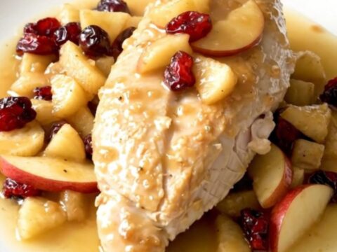 Slow cooker apple cranberry chicken served on a white plate with visible steam.