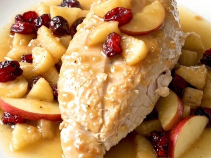 Slow cooker apple cranberry chicken served on a white plate with visible steam.