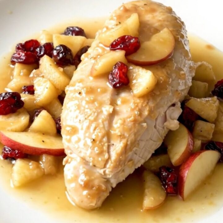 Slow cooker apple cranberry chicken served on a white plate with visible steam.