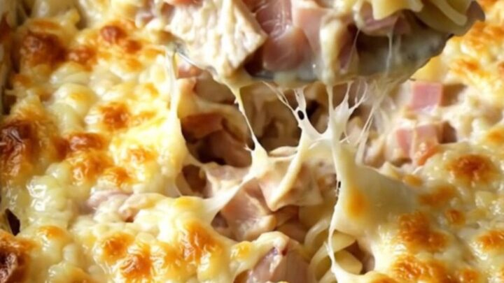 A creamy Chicken Cordon Bleu pasta bake in an enamel dish with golden melted Swiss cheese.