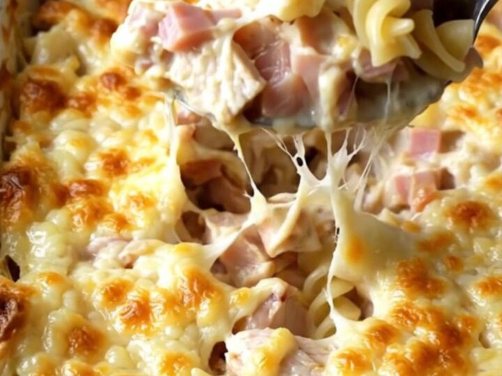 A creamy Chicken Cordon Bleu pasta bake in an enamel dish with golden melted Swiss cheese.