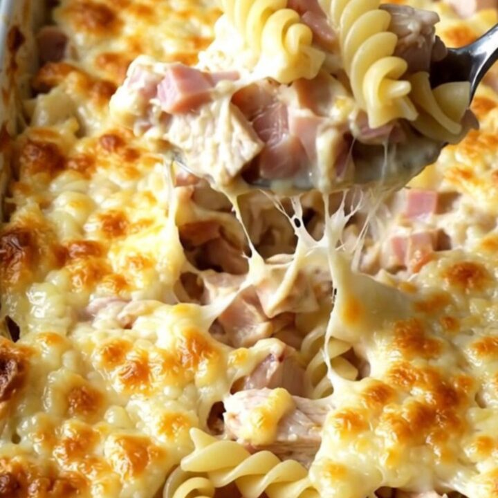 A creamy Chicken Cordon Bleu pasta bake in an enamel dish with golden melted Swiss cheese.