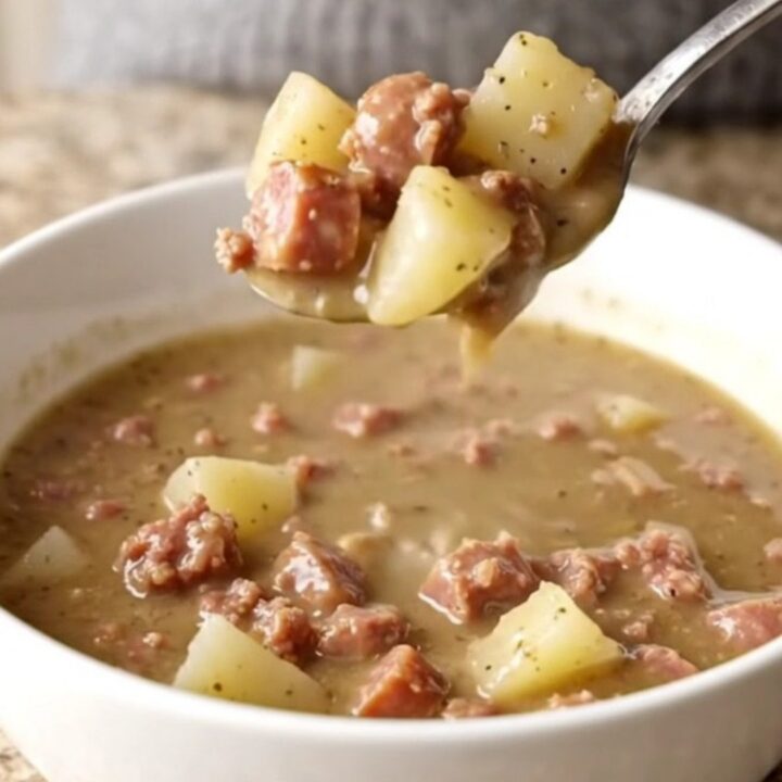 A bowl of creamy sausage and potato soup with visible sausage crumbles and tender potato chunks in a thick gravy.