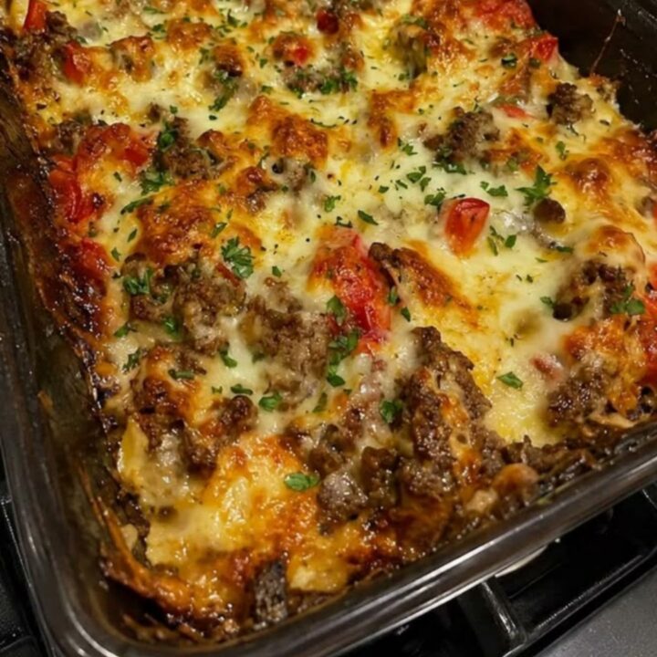 A close-up of a Philly cheesesteak casserole with melted mozzarella cheese and steam rising.