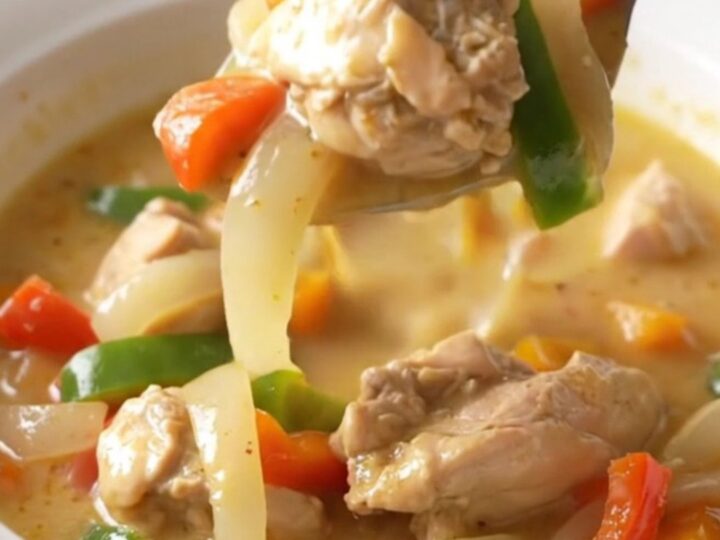 A bowl of creamy Philly chicken cheesesteak soup with visible chicken strips, peppers, and onions.