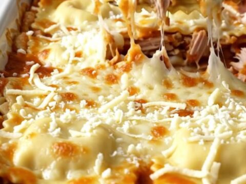 A top-down view of a rectangular baking dish filled with layers of ravioli, turkey, and melted mozzarella cheese.
