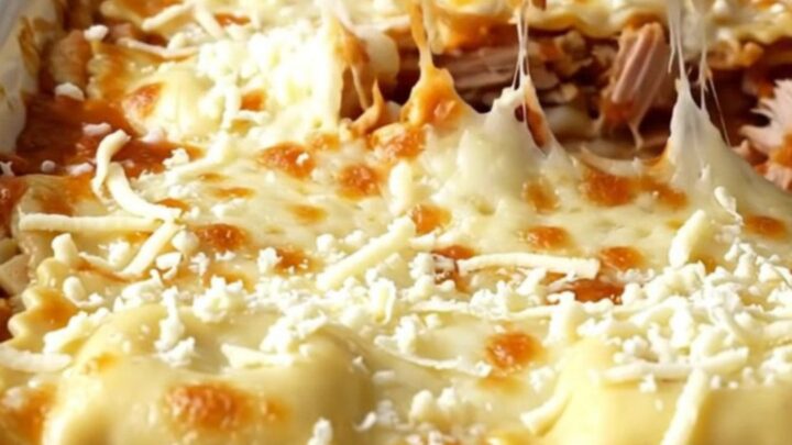 A top-down view of a rectangular baking dish filled with layers of ravioli, turkey, and melted mozzarella cheese.