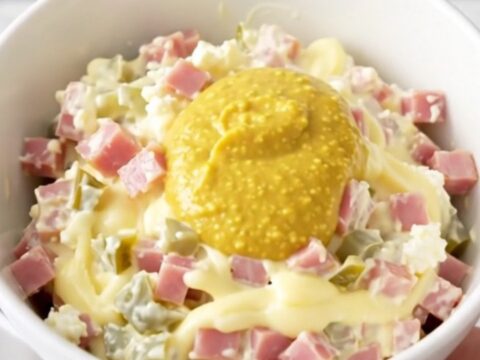 A close-up of the finished Cuban sandwich dip in a white bowl with visible ham and pickle pieces.