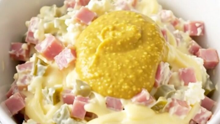 A close-up of the finished Cuban sandwich dip in a white bowl with visible ham and pickle pieces.