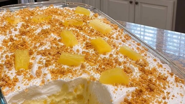 A close-up of a square slice of no-bake pineapple cream dessert showing distinct layers of graham crust and creamy pineapple