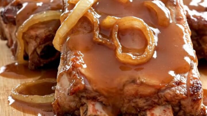 A stack of tender, slow-cooked baby back ribs glazed in a rich, shiny honey barbecue sauce on a rustic wooden board.