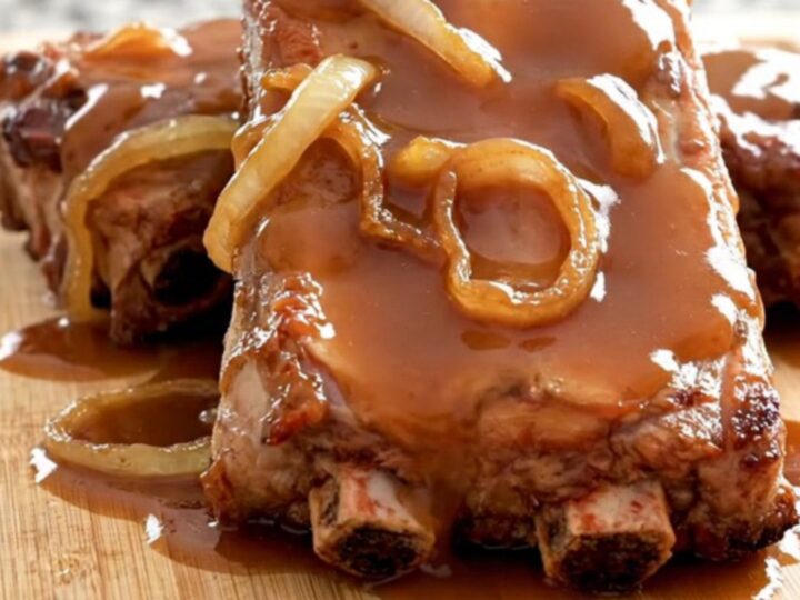 A stack of tender, slow-cooked baby back ribs glazed in a rich, shiny honey barbecue sauce on a rustic wooden board.