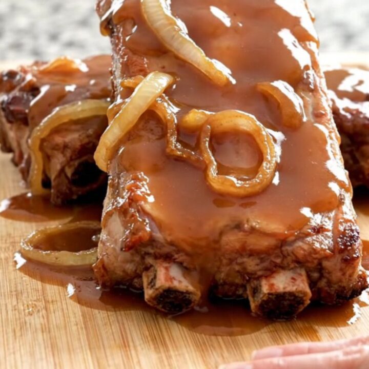 A stack of tender, slow-cooked baby back ribs glazed in a rich, shiny honey barbecue sauce on a rustic wooden board.
