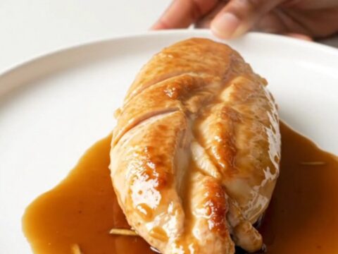 A close-up of tender, slow-cooked chicken breasts coated in a glossy
