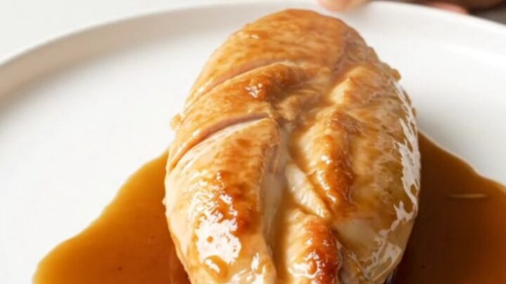 A close-up of tender, slow-cooked chicken breasts coated in a glossy