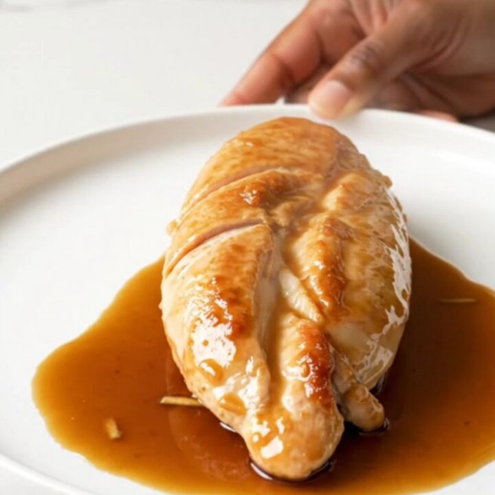 A close-up of tender, slow-cooked chicken breasts coated in a glossy