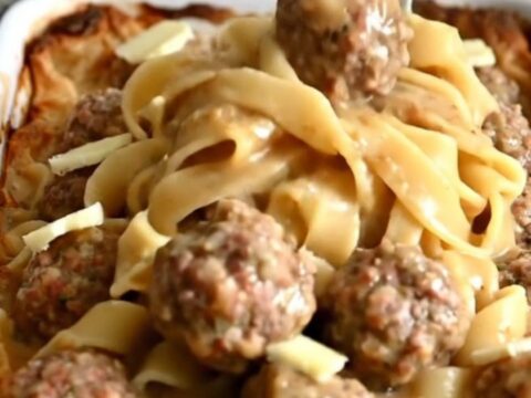 A top-down view of a rectangular baker filled with egg noodles and Swedish meatballs in a creamy gravy.