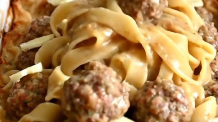 A top-down view of a rectangular baker filled with egg noodles and Swedish meatballs in a creamy gravy.