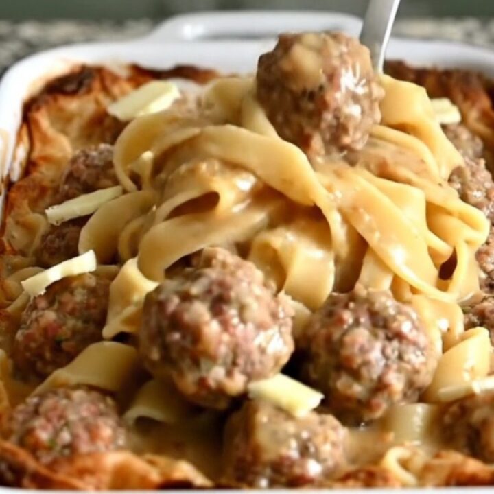 A top-down view of a rectangular baker filled with egg noodles and Swedish meatballs in a creamy gravy.