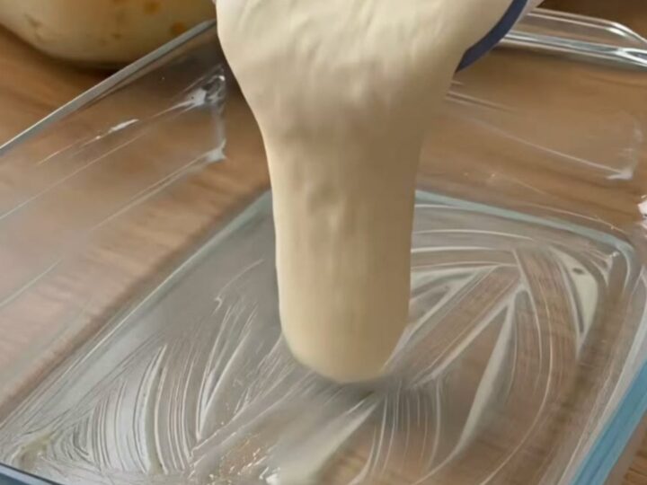 A close-up of a creamy baked coconut dessert in a glass dish with a golden, toasted coconut topping.
