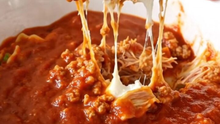 A black slow cooker filled with layers of ground turkey, ricotta, mozzarella, and marinara sauce.