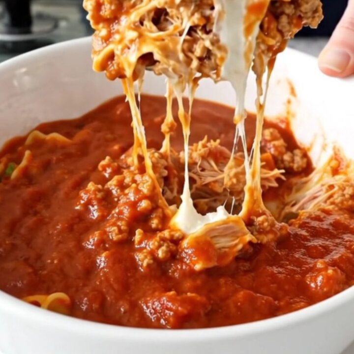 A black slow cooker filled with layers of ground turkey, ricotta, mozzarella, and marinara sauce.