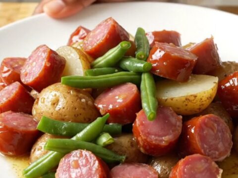Close-up view of the finished lemon pepper kielbasa, green beans, and potatoes in a slow cooker.
