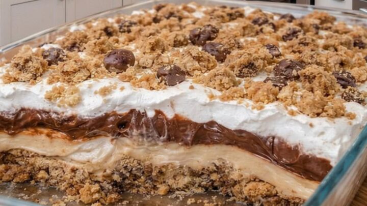 A slice of no-bake peanut butter pie with clear layers of cookie crust, peanut butter filling, chocolate ganache