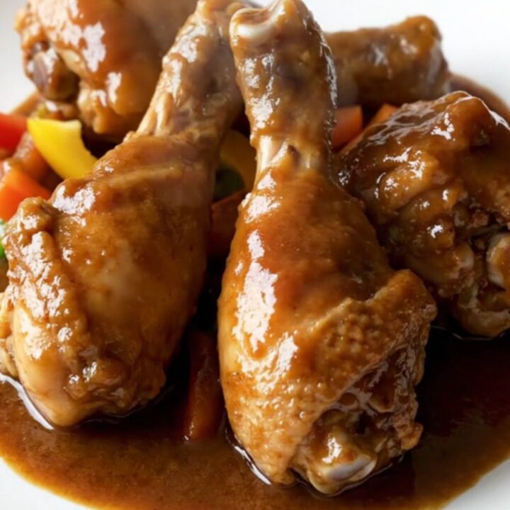 A close-up of tender Jamaican brown stew chicken with dark gravy in a slow cooker.