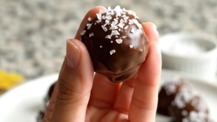 A plate of chocolate-dipped peanut butter buckeyes sprinkled with flaky salt.