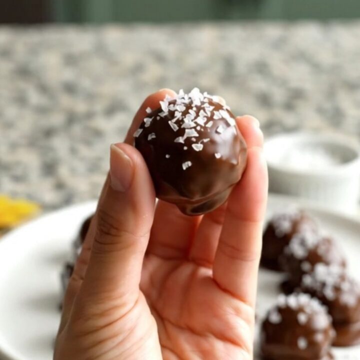 A plate of chocolate-dipped peanut butter buckeyes sprinkled with flaky salt.