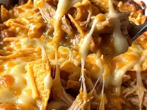 A top-down view of a golden, bubbling nacho cheese and chicken casserole in a white rectangular dish.