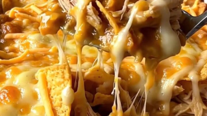 A top-down view of a golden, bubbling nacho cheese and chicken casserole in a white rectangular dish.