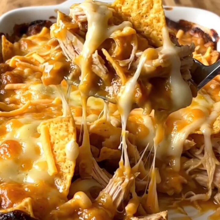 A top-down view of a golden, bubbling nacho cheese and chicken casserole in a white rectangular dish.