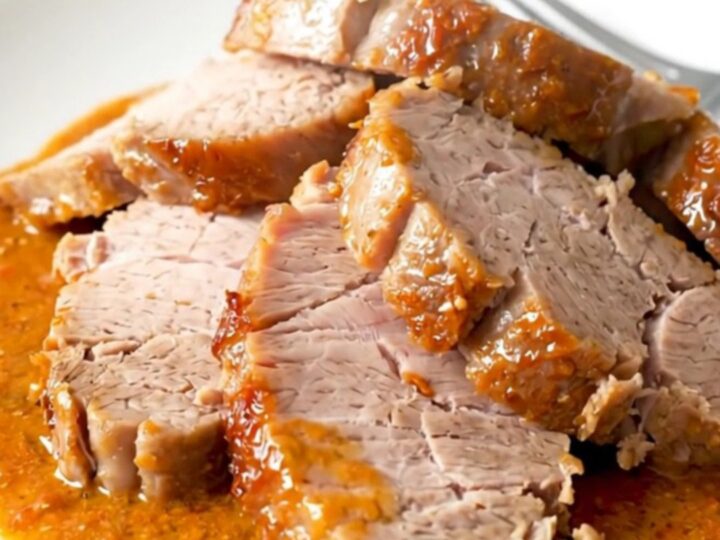 A top-down view of a crockpot filled with raw pork tenderloin, sun-dried tomatoes, and a creamy sauce.
