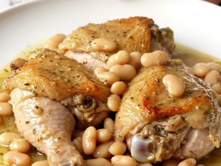 A slow cooker filled with creamy chicken thighs and butter beans in a rich garlic sauce.